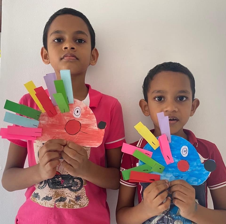 Two boys proudly holding their handmade paper hedgehog puppets