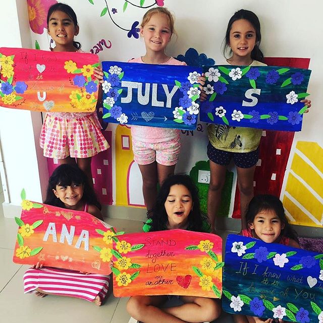 A group of kids holding up their hand-painted lettering and flower artwork