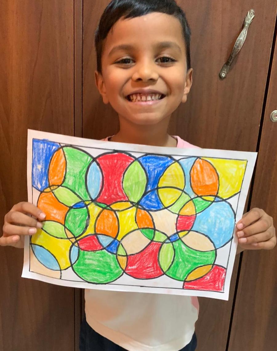 A boy holding up his overlapping-circles pattern drawing