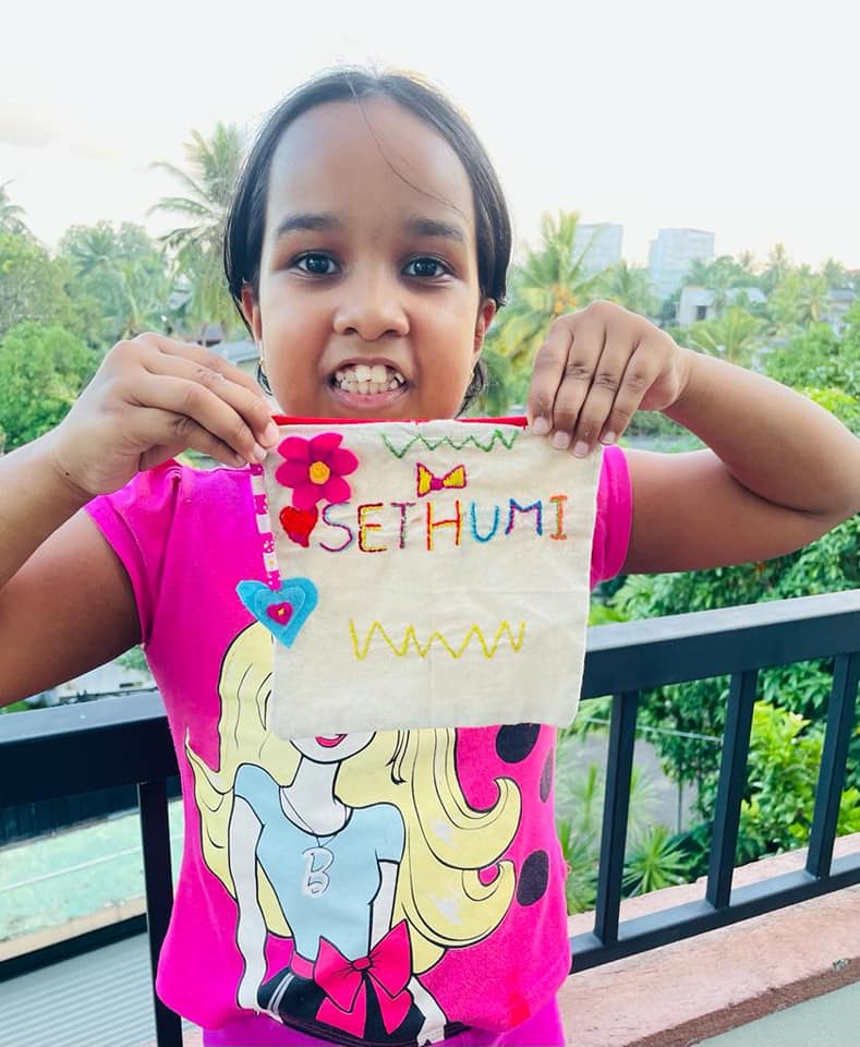 A girl holding up her embroidered zipper pouch with her name stitched on it
