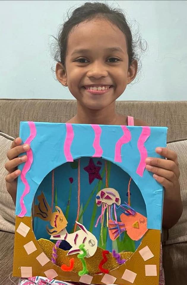 A girl holding her paper-craft undersea aquarium diorama