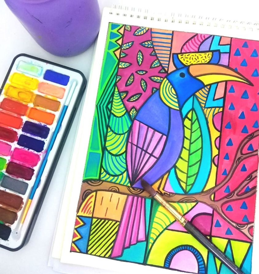A watercolor painting of a toucan in progress next to an open paint palette