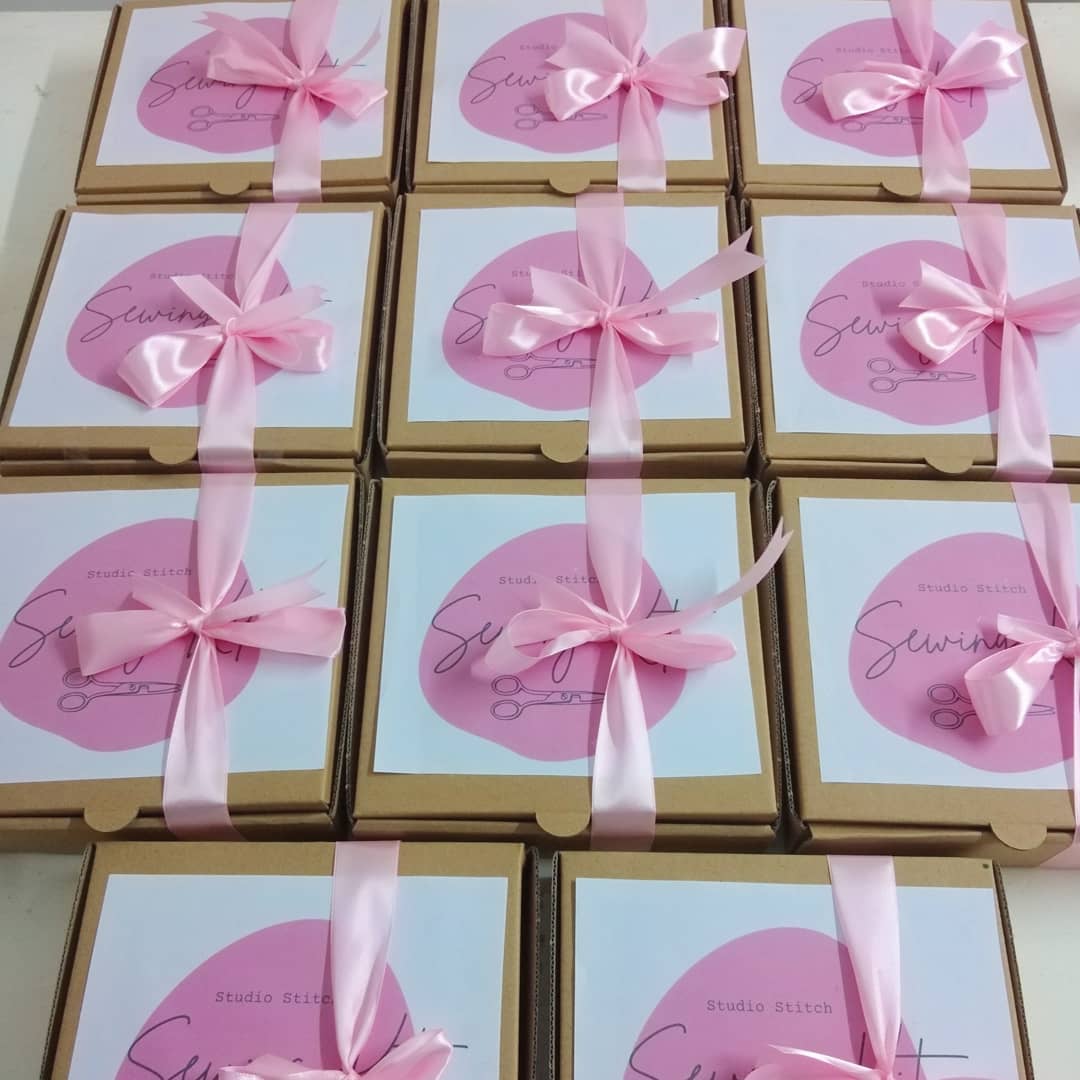 A stack of ribbon-tied Studio Stitch sewing kit boxes ready for pickup